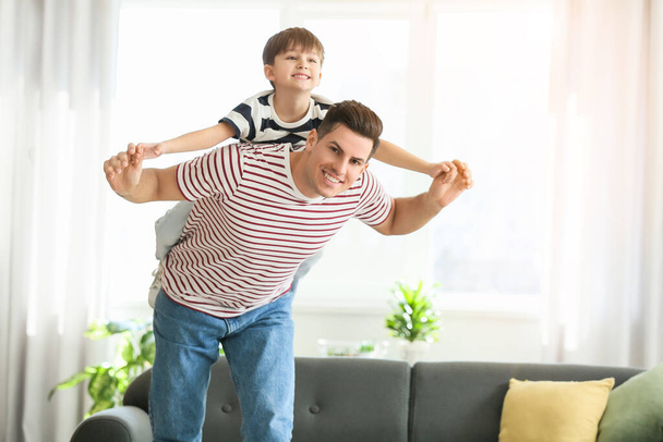 Ο ευτυχισμένος πατέρας και ο μικρός γιος του παίζουν στο σπίτι. - Φωτογραφία, εικόνα