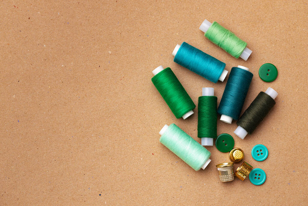 Thread spools and buttons on beige background - Photo, image