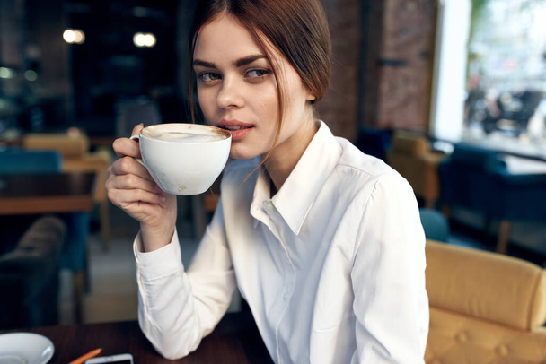 portrait d'une belle femme avec une tasse à la main dans un restaurant et intérieur en arrière-plan - Photo, image