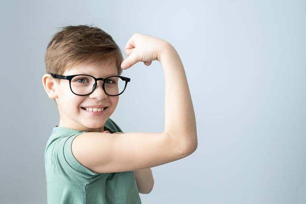 strength boy in a green T-shirt and glasses pensive. Copy space - Photo, Image