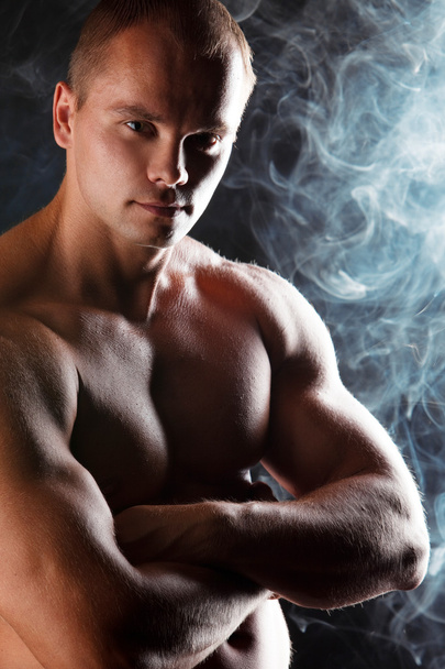 Young sporty man over Smoke. Muscles, a close up - Foto, Bild
