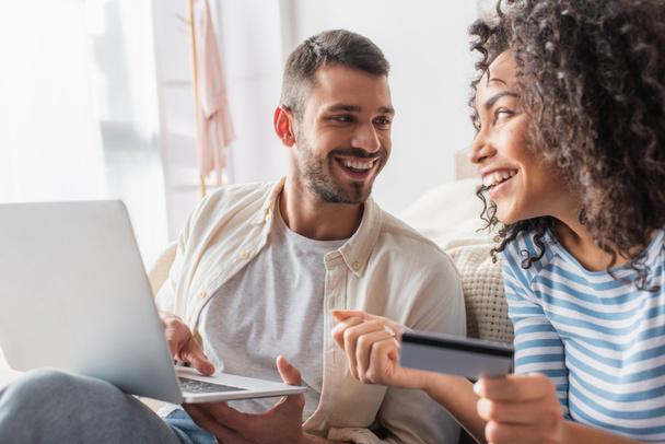 szczęśliwy międzyrasowy para zakupy online podczas korzystania z laptopa - Zdjęcie, obraz