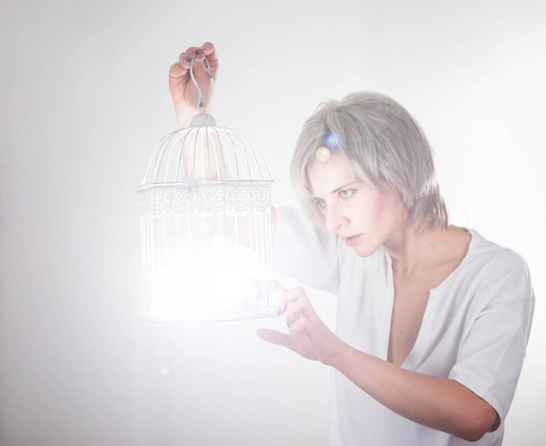 young blond woman catches a light to a bird cage - Φωτογραφία, εικόνα