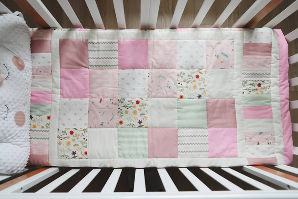 Cozy baby cot with pink patchwork blanket. Baby bedding. Bedding and textile for nursery. Nap and sleep time - Foto, imagen