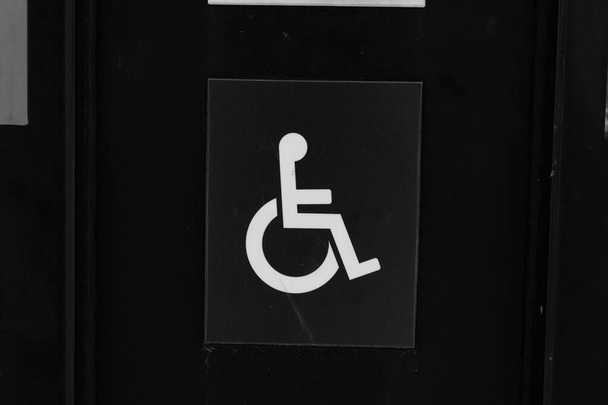 Large white signs of disabled person on dark wood doors, close up - Photo, Image
