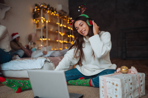 Female with antlers while speaking with online friend on laptop - Photo, image