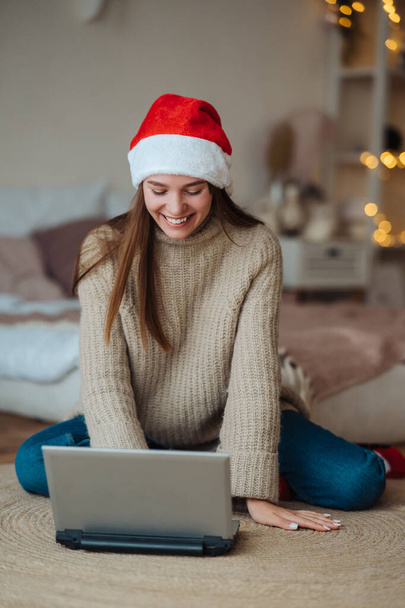 Donna che indossa il cappello di Babbo Natale mentre parla con un amico online sul computer portatile - Foto, immagini