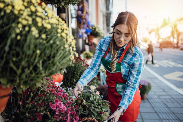 Young adult woman working in city street flower shop or florist. Small business concept. - Fotografie, Obrázek