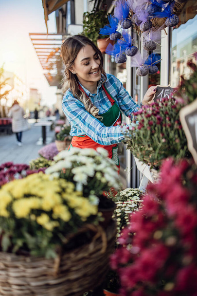 Young adult woman working in city street flower shop or florist. Small business concept. - Photo, Image