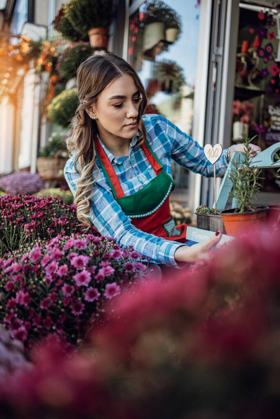Young adult woman working in city street flower shop or florist. Small business concept. - Photo, Image