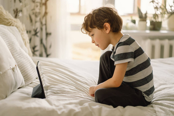 Little Boy met een tablet in de kamer. De jongen speelt spel op de tablet. Technologie concept. Kind met een gadget - Foto, afbeelding