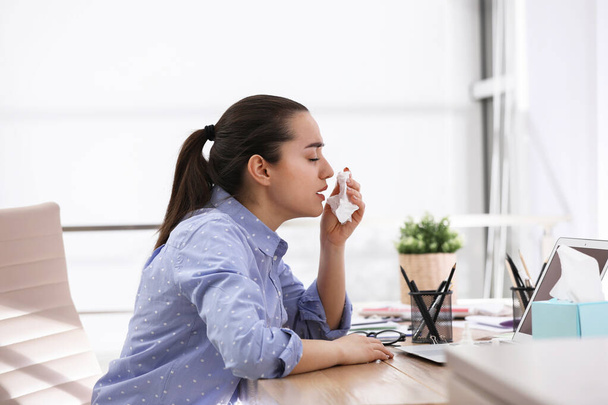 Sick young woman with napkin in office - Fotografie, Obrázek