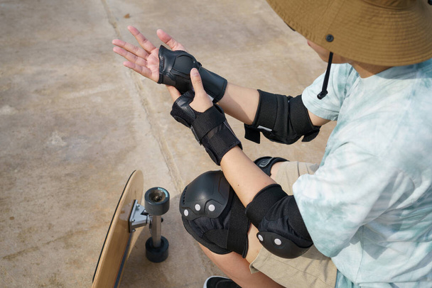 Skateboard safety gear and pads. Asian man with surfboards or surf skate around city streets background on a summer day. Free relax lifestyle and millennial trend concept - Φωτογραφία, εικόνα