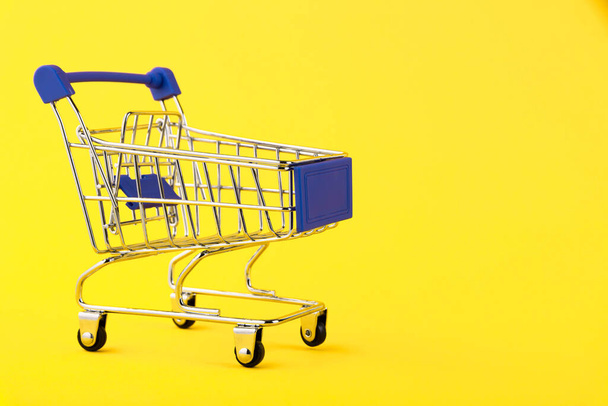 Empty mini shopping trolley, Shopping cart, on a yellow background. RFI Request for information. copy space - Foto, afbeelding