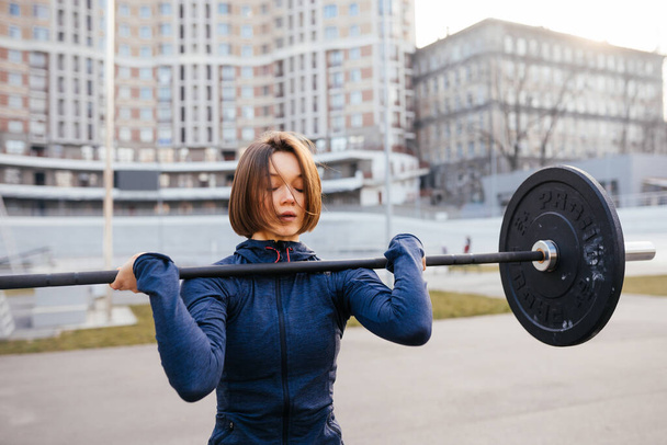 Mujer fuerte haciendo ejercicio con barra. Deportes, concepto de fitness. - Foto, imagen