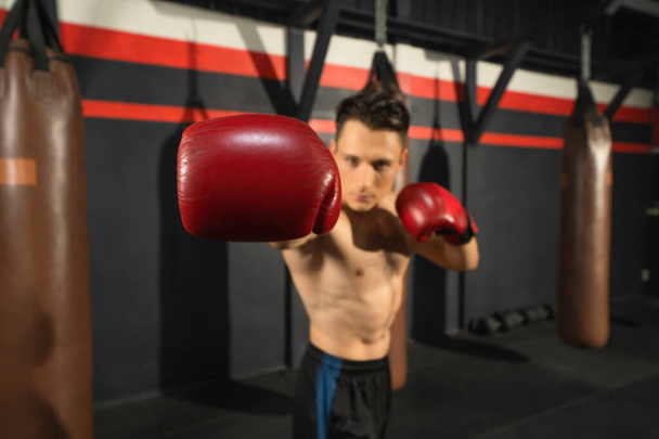 Портрет сильного бійця, який позує м'язи, ударяючи бойовими ударами у тренуваннях боксерського спортивного клубу на тренувальному фітнес-центрі. Тренування в приміщенні спортивного обладнання. Люди стиль життя
. - Фото, зображення