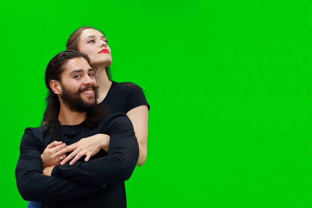 Сексуальная женщина обнимает улыбающегося мужчину на зеленом фоне хромы. На центральном хромовом фоне есть место для рекламы.. - Фото, изображение
