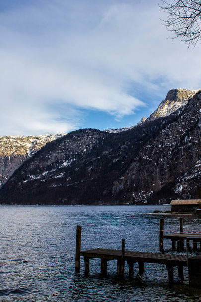 Vista de un muelle antiguo y el lago Hallstatt con montañas en el fondo - Foto, Imagen