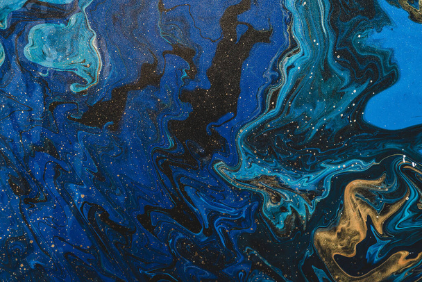 金色の青の色合いの流体芸術の背景。液体インクの流れ波効果。黄金の汚れとダークファントムブルー。アクリル絵具のファンタジー抽象的な質感。超現実的な色のミックス。青の金. - 写真・画像