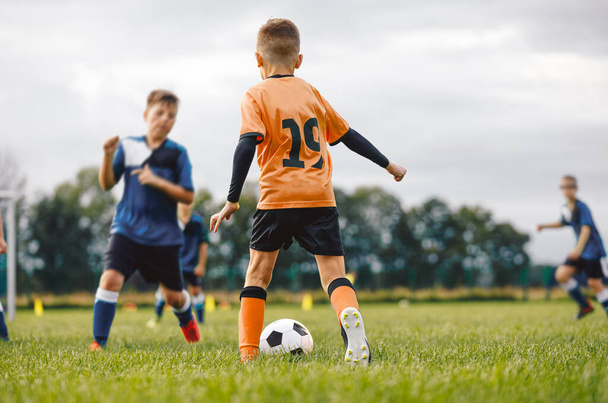 Αγόρια σε δύο ποδοσφαιρικές ομάδες Παίζοντας το παιχνίδι στο γρασίδι. Σχολικά παιδιά κλωτσάνε μπάλα ποδοσφαίρου. Αθλητική Εκπαίδευση για Παιδιά. Αθλητισμός Εξωτερική δραστηριότητα για νεαρά αγόρια - Φωτογραφία, εικόνα