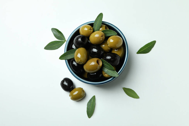 Bowl of olives and leaves on white background, top view - Fotó, kép