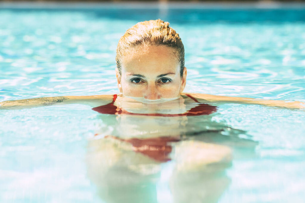 Portret kobiety z twarzą w dół do wody przy basenie i oczami na zewnątrz patrzącymi w kamerę - Zdjęcie, obraz