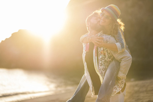 Erwachsenes Paar hat Huckepack-Spaß, Mann trägt Frau und lacht viel mit Liebe und Glück am Strand bei Sonnenuntergang  - Foto, Bild