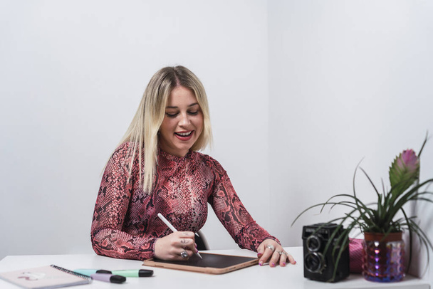 A young Caucasian female from Spain working and taking notes on a tablet with a smartpen - Foto, imagen