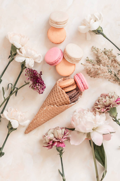 A top view of the sweet colorful macarons in the waffle cone on the light brown surface - Fotoğraf, Görsel