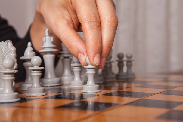 Satranç oynayan kadın hamlesini yapıyor. İş stratejisi ve taktik kavramı. - Fotoğraf, Görsel