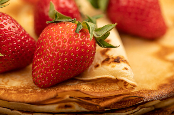 Verse rode aardbeien en traditionele Russische pannenkoeken. Shrovetide week. Close-up, selectieve focus. - Foto, afbeelding