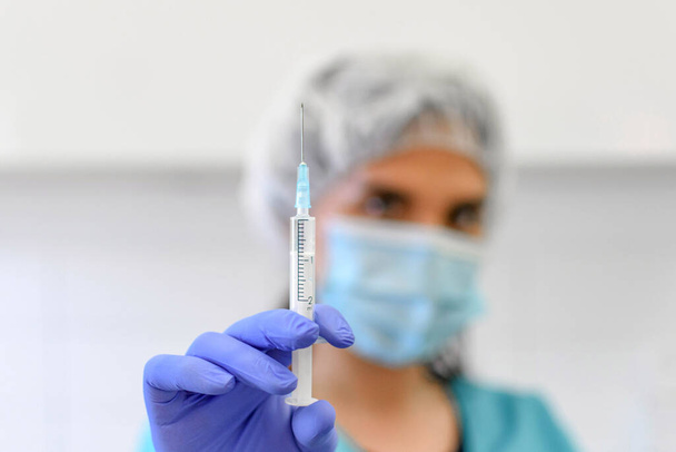 Selective focus image of medical worker holding syringe. Vaccine, vaccination, injection. - Фото, изображение