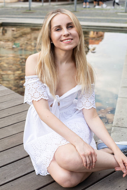 Smiling white european young model with a blonde hair sitting on the city street - Foto, immagini
