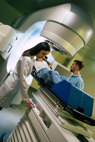Cancer treatment in a modern medical private clinic or hospital with a linear accelerator. Professional doctors team working while the woman is undergoing radiation therapy for cancer - Valokuva, kuva
