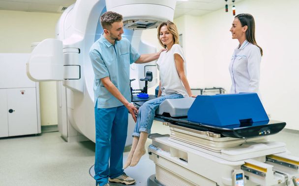 Cancer treatment in a modern medical private clinic or hospital with a linear accelerator. Professional doctors team working while the woman is undergoing radiation therapy for cancer - Foto, afbeelding