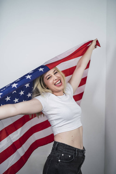 A vertical shot of a smiling Spanish female with the flag of USA - 写真・画像