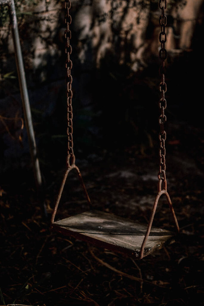 An empty grungy abandoned swing full of memories, the end of childhood, no people around - Foto, immagini
