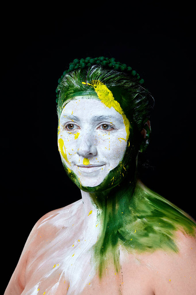 Πορτραίτο μιας γυναίκας με ζωγραφισμένο πρόσωπο. Δημιουργικό μακιγιάζ και φωτεινό στυλ.Κορίτσι με χρωματιστό πρόσωπο βαμμένο. Art beauty image.girl με πολύχρωμο χρώμα στο πρόσωπό της.  - Φωτογραφία, εικόνα