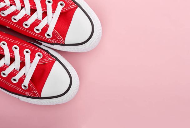 Red sneakers on pink background with copy space. Youth shoes. - Foto, afbeelding