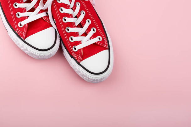 Red sneakers on pink background with copy space. Youth shoes. - Φωτογραφία, εικόνα