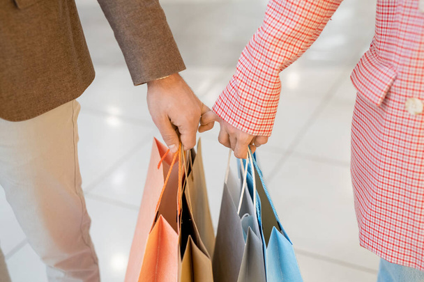 Primer plano de pareja encantadora sosteniendo bolsas de compras durante las compras - Foto, imagen
