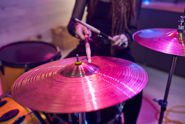 Close-up of female drummer using sticks while playing on drums during performing - Photo, Image