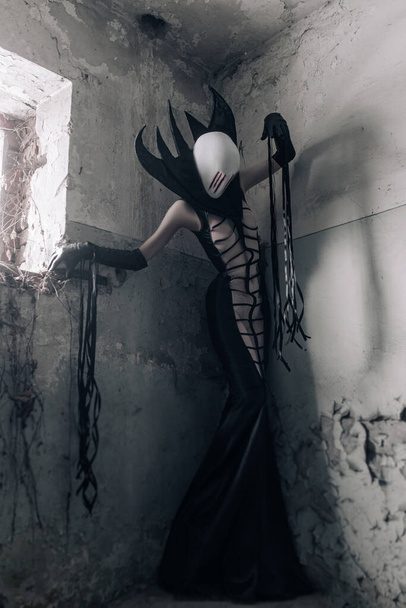 Женщина по образу инопланетного существа стоит внутри старого заброшенного дома. - Фото, изображение