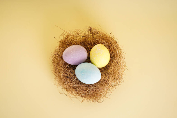 Easter eggs in a nest on a yellow background, flat lay. - Valokuva, kuva