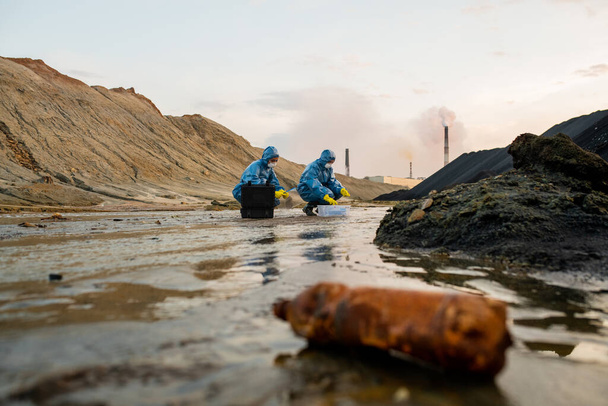 ゴム手袋、保護カバー、眼鏡、呼吸器の2つの生態学者は、危険な領域で毒性水の特性を研究 - 写真・画像