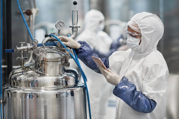 Portret pracowniczki noszącej kombinezon ochronny podczas obsługi sprzętu w nowoczesnym zakładzie chemicznym, przestrzeń do kopiowania - Zdjęcie, obraz