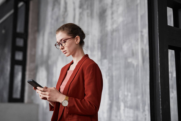 Портрет молодої бізнес-леді в червоному, стоячи на сірій стіні в офісі, копіювати простір
 - Фото, зображення