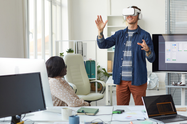 Portrait de l'équipe de développement informatique concevant des logiciels de réalité immersive avec un accent sur l'homme portant un casque VR dans le bureau, espace de copie - Photo, image