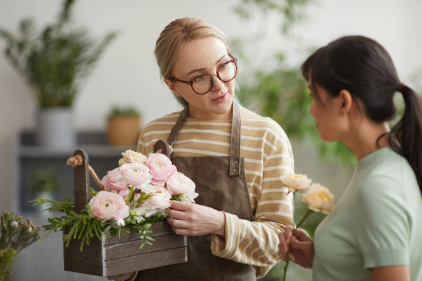 Талия портрет молодой женщины, дающей букет клиенту во время работы в цветочном магазине - Фото, изображение