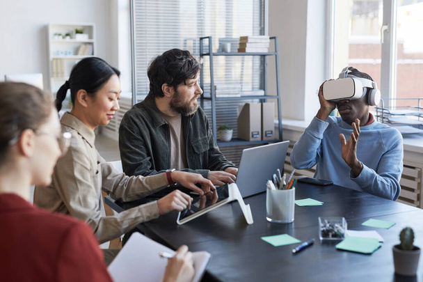 Portrait of diverse IT team developing software for virtual reality project during meeting in office, focus on African-American man using VR - Foto, afbeelding